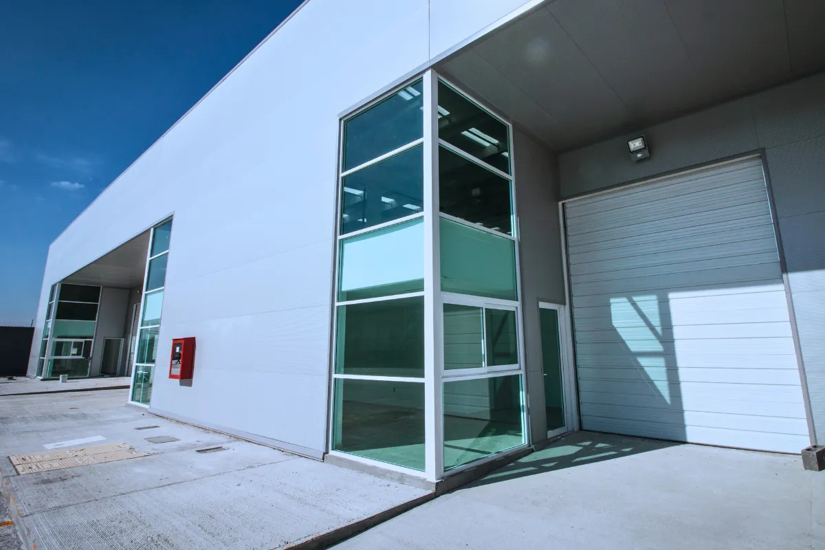 Detalle de fachada industrial con cristal y panel metálico construida por Fachadismo